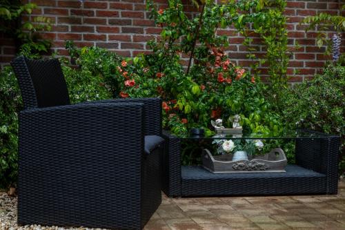 two wicker chairs and a glass table with plants at Hotel De Pastorij in Leuven