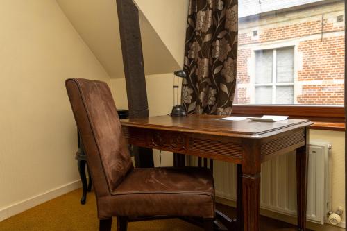 a wooden desk with a chair next to a window at Hotel De Pastorij in Leuven