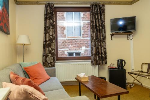 a living room with a couch and a window at Hotel De Pastorij in Leuven