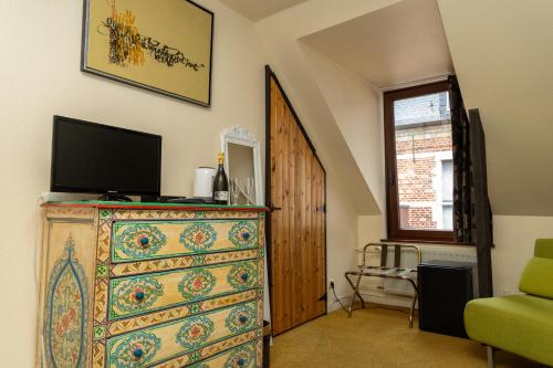 a dresser with a television on top of it at Hotel De Pastorij in Leuven