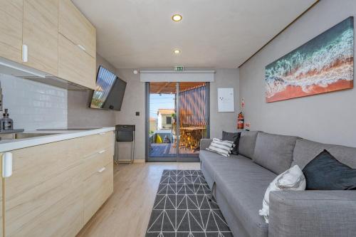 a living room with a gray couch and a kitchen at Fajã Lodges - Studio Ash in São Vicente
