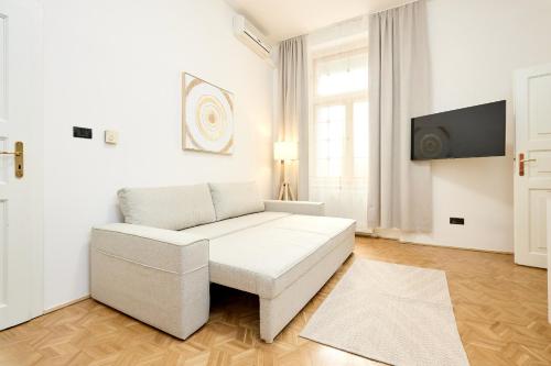 a living room with a white couch and a tv at Alma Apartments in Prague