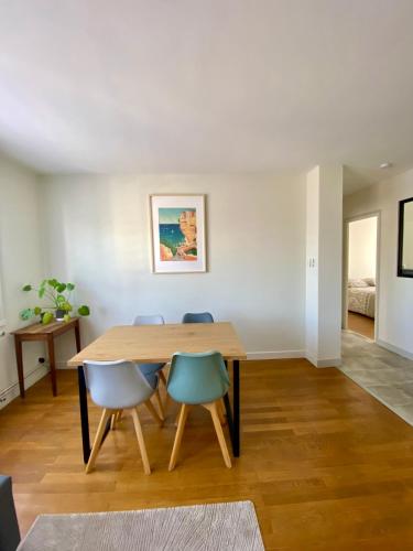 une salle à manger avec une table en bois et des chaises bleues dans l'établissement Appart cozy - 2 chambres, à deux pas du centre ville, à Chalon-sur-Saône
