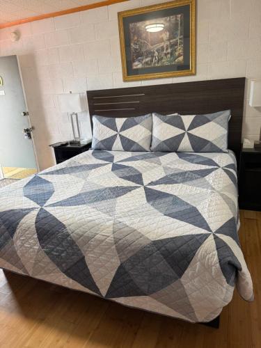 a bedroom with a bed with a black and white quilt at Starlight Motel in Big Pine