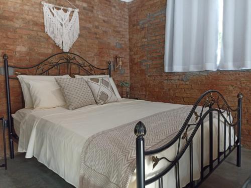 a bed in a bedroom with a brick wall at Vale Infinito Chalé in Córrego do Bom Jesus