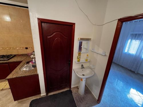 a bathroom with a wooden door and a sink at Family apartment 350m la plage in Ras El Ma