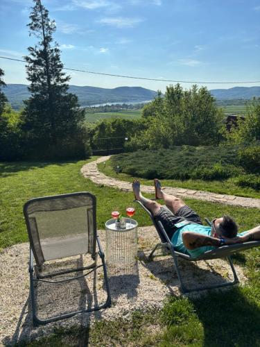 a man laying in a lawn chair next to a mirror at Szarvas Vendégház in Zebegény
