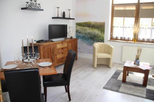 a living room with a dining table and a television at Meine Fischerhütte in Börgerende-Rethwisch
