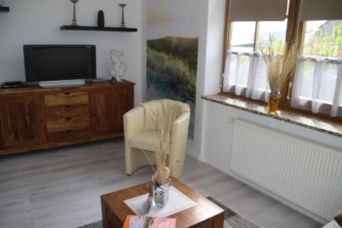 a living room with a tv and a chair and a table at Meine Fischerhütte in Börgerende-Rethwisch