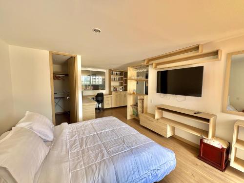 a bedroom with a bed and a flat screen tv at Apartamento con amplia zona de trabajo in Rionegro