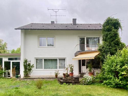 a white house with a porch and a balcony at Estelada Boarding Houses Oberhaching in Oberhaching