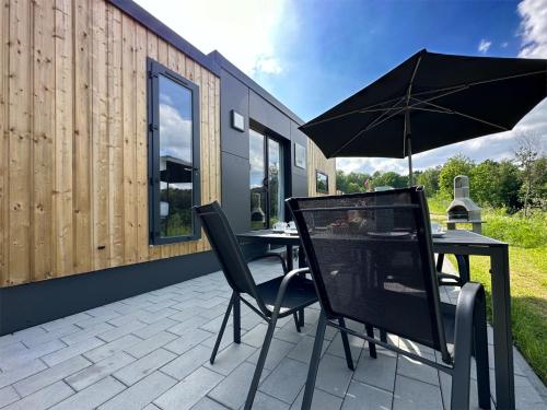 a table and chairs with an umbrella on a patio at tiny house am See, Neunburg vorm Wald in Neunburg vorm Wald