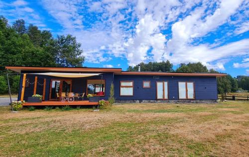 a small blue house with a large yard at Casa con vista al Lago y Volcan JW in Molco