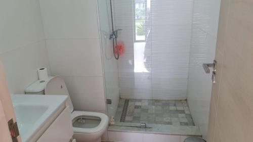 a white bathroom with a shower and a toilet at Ground floor apartment - Residence Skhirat Beach 2 in Skhirat