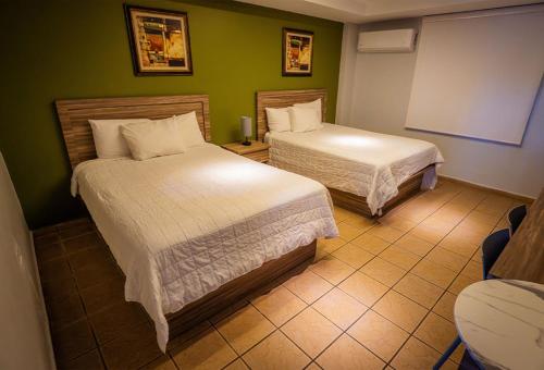 two beds in a room with green walls at Hotel Vista Azul in Aguadilla