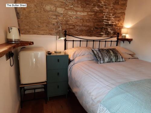 a bedroom with a bed and a brick wall at Cotswold Cottage B&B - 5 Minutes Walk to Village Pub in Luckington