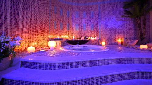 a bathroom with a tub with candles and purple lights at Sirena Residence & Spa in Marathokampos