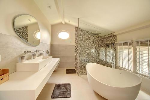 une salle de bain avec deux lavabos, une baignoire et un miroir dans l'établissement Superbe Mas Provençal rénové avec piscine, billard et climatisation à Paradou, à Paradou