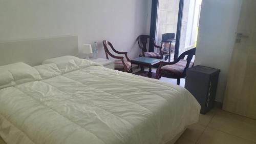 a bedroom with a bed and chairs and a window at Ground floor apartment - Residence Skhirat Beach 2 in Skhirat