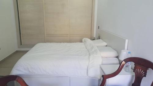 a bedroom with a white bed and a chair at Ground floor apartment - Residence Skhirat Beach 2 in Skhirat