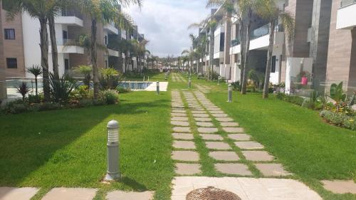 a walkway in the middle of a lawn with palm trees at Ground floor apartment - Residence Skhirat Beach 2 in Skhirat
