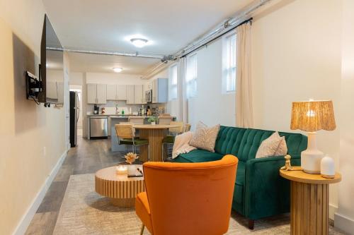 Una sala de estar con un sofá verde y una cocina. en Moderno 1BR - Parking - 15 min NYC, en Jersey City