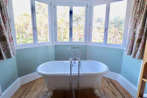 - une baignoire blanche dans une chambre avec fenêtres dans l'établissement L'Orénoque Duplex en forêt, à Le Touquet-Paris-Plage