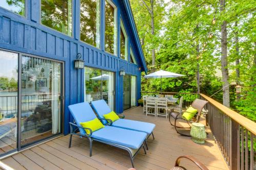 a blue house with two chairs and a table on a deck at Beautiful Lake Keowee Home with Boat Dock and Fire Pit in Seneca