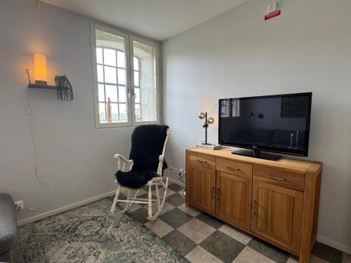 a living room with a flat screen tv and a chair at Spacious & elegant apartment in a stable at Kvarnviks Gård in Klagstorp