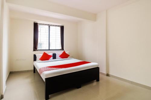a bedroom with a bed with red pillows and a window at Hotel O Galaxy Near INOX in Yeraoda