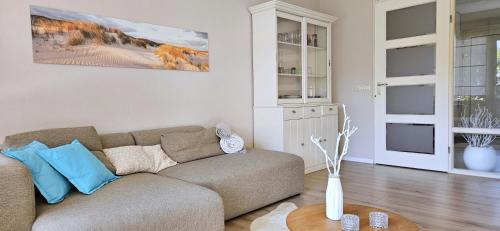 a living room with a couch and a table at Strandnahes Ferienhaus mit Garten hundefreundlich MeerZeit Ameland in Buren