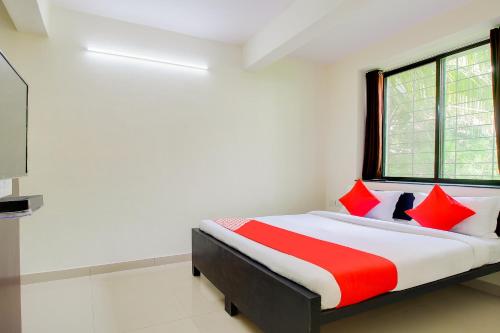a bedroom with a bed with red and white pillows at Hotel O Galaxy Near INOX in Yeraoda