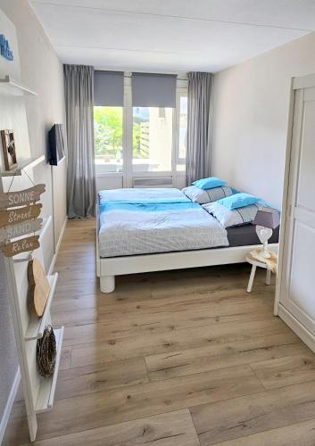 a bedroom with a bed and a large window at Strandnahes Ferienhaus mit Garten hundefreundlich MeerZeit Ameland in Buren