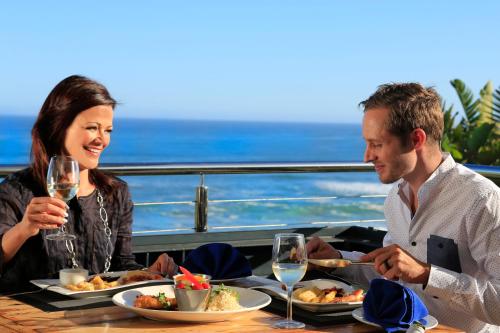 a man and woman sitting at a table with food and wine at Brenton Haven Beachfront Resort in Knysna