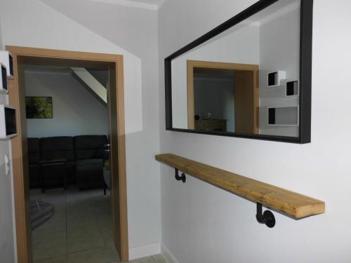 a mirror on a wall with a wooden shelf at Bakumara in Bakum
