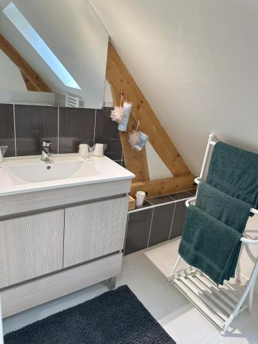 La salle de bains est pourvue d'un lavabo et d'une chaise. dans l'établissement Gite des 3 sœurs, à Vernon