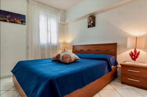 una camera da letto con un letto con lenzuola blu e una finestra di Scalingi Family Apartments a Sperlonga