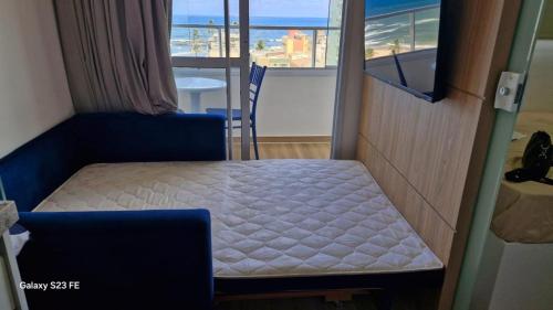 a small bed in a room with a view of the ocean at Apt lindo e novo vista mar com garagem orla de Pituba in Salvador