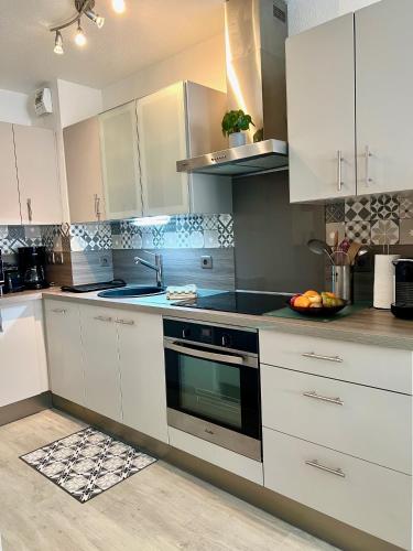 une cuisine avec des armoires blanches et un four à plaques de cuisson dans l'établissement Les Océanes, à Les Sables-dʼOlonne