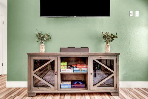 a television on top of a wooden cabinet with two vases at Magnolia Peaceful Vibes Cozy Near Hospital in Hanford