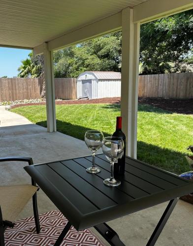 a black table with two glasses and a bottle of wine at Magnolia Peaceful Vibes Cozy Near Hospital in Hanford