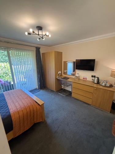 a hotel room with a bed and a desk and a television at Barncroft Luxury Bed & Breakfast in Solihull