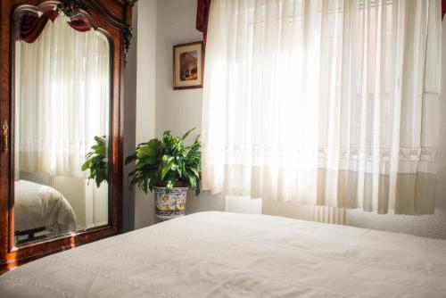 a bedroom with a bed and a mirror and a window at Casa Montesol in Cáceres
