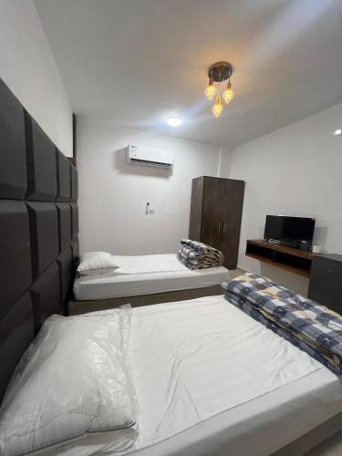 a room with two beds and a television in it at Camel Dive Club By The Sea Inn in Jurf ad Darāwīsh