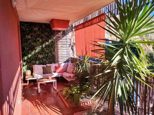 une terrasse avec un canapé et un palmier dans l'établissement T2 moderne, à Balaruc-les-Bains