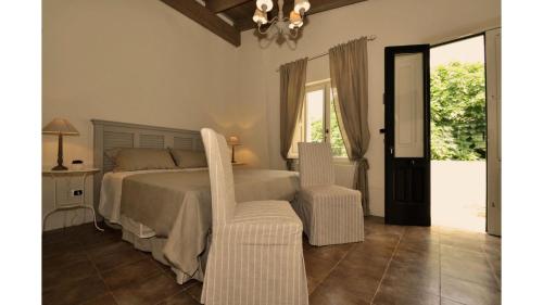 a bedroom with a bed and two white chairs at Don Alfonso Dimora D'epoca in Racale