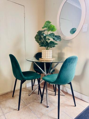 a dining room table with two green chairs and a mirror at Private Studio in Cape Town, Near Canal Walk & Table Mountain in Cape Town