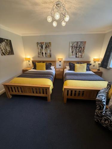 a bedroom with two beds and a chandelier at Barncroft Luxury Bed & Breakfast in Solihull