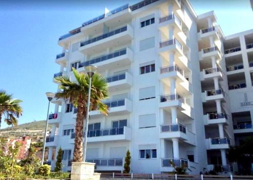 un bâtiment blanc avec un palmier devant dans l'établissement Jonian Waves, à Saranda