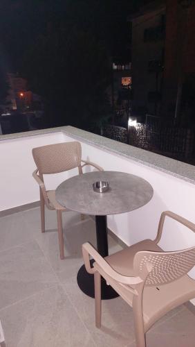 a table and two chairs on a balcony at night at Vila REJANA in Ksamil
